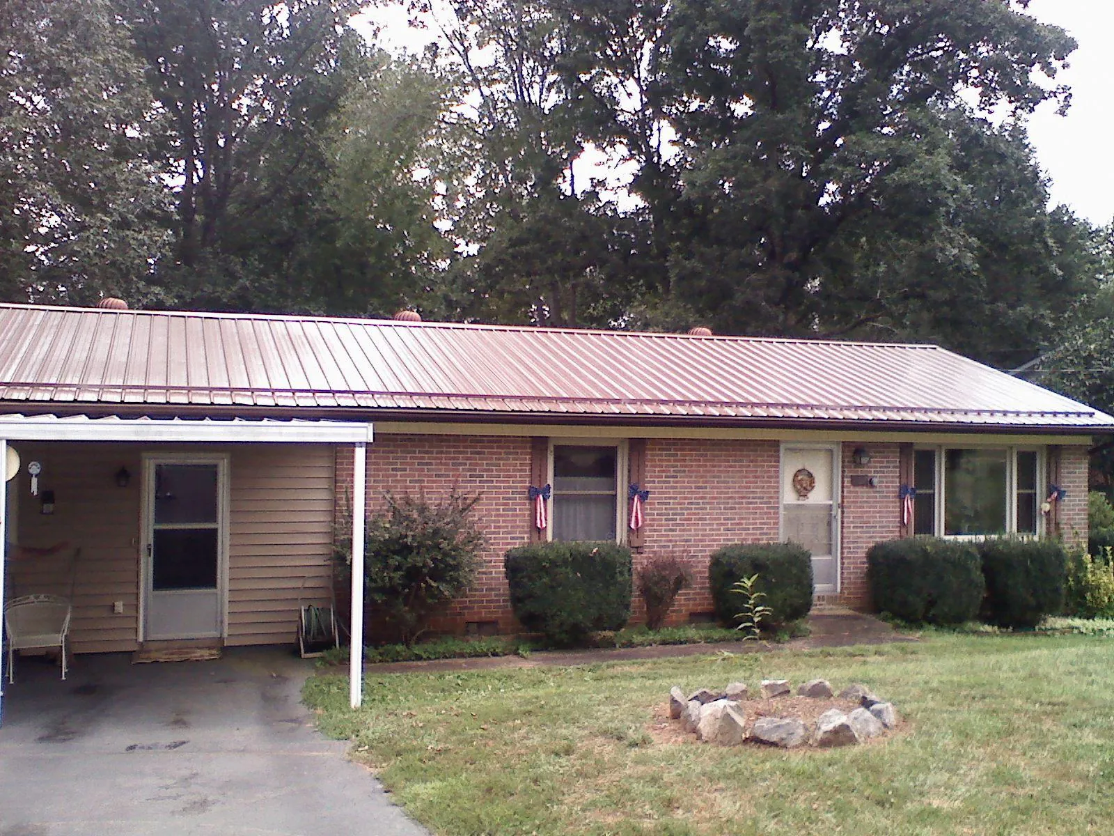 Bronze metal roof and carport on a brick ranch home — Roof Repair work by our crew in Johnstown